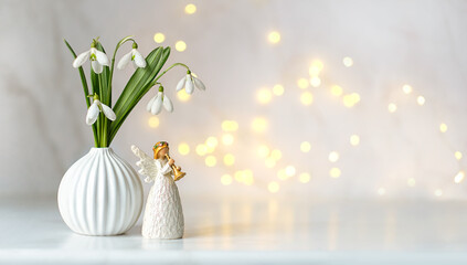 Cute angel and snowdrops flowers on table, light abstract background. Religious church holiday....