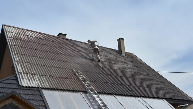 Worker cleaning the roof, pressure cleaning with water before spraying the paint