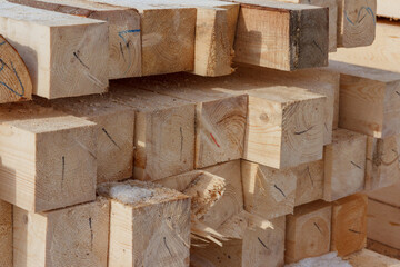 Stack of wooden squared beams for construction. Material for the construction of a wooden building. Closeup big wooden boards. Warehouse of wooden beams.