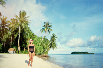Vacation on the seashore.Young woman walking on the beautiful tropical white sand beach.