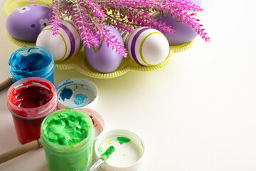 Brushes and open jars with gouache paint red, green, blue lie on a white background, prepared for...