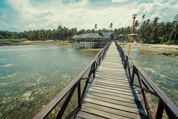 Fototapeta na wymiar Beautiful landscape. Sunny day on seashore. Wooden bridge on Cloud 9 beach, Siargao Island Philippines.