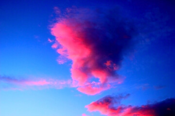 Ethereal soft pink clouds illuminated on the one side and shaded on the other one in the blue sky after sunset in Monte Vidon Corrado