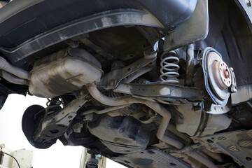 A modern car in a car service on a lift with the wheels removed. The structure of the rear suspension and its elements are visible. Selected focus.