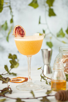 A rum sour cocktail with egg white foam and a dried orange slice garnish.