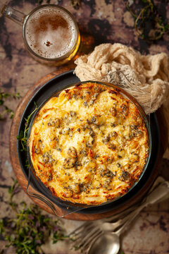 A Savoury Meat Pie Topped With Mashed Potato And Blue Cheese And Served With A Glass Of Beer.