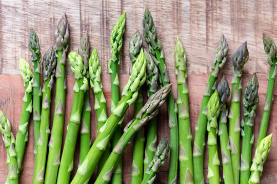 Asparagus spears on a textured wooden background.