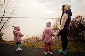 Mother with daughters walking on the path by the lake.