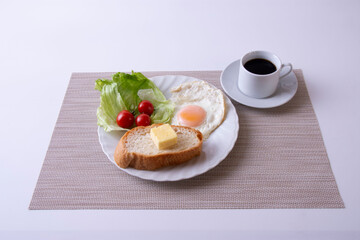 トーストや卵を調理した物をお皿に盛り付けた朝食のイメージ