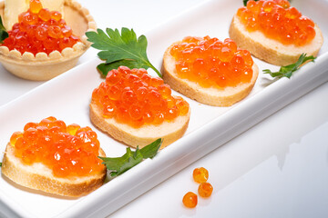 Red Caviar on butter sandwich in white plate on white background close-up. Sandwich with red fish caviar diet breakfast in morning.