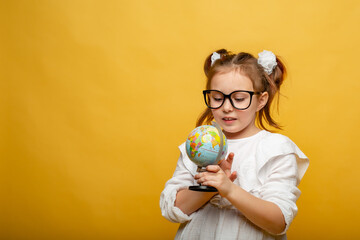 a cute six-year-old girl holds a mock-up of the Earth in her hands and examines it