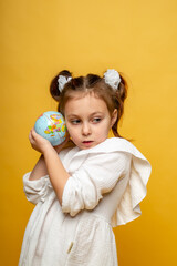a cute six-year-old girl hugs a mock-up of the Earth