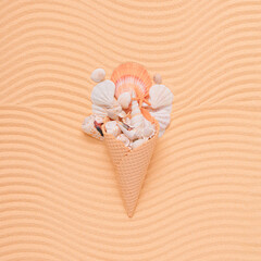 Creative summer layout with sea shells and ice cream cone on sandy wavy background. Minimal beach food concept. Flat lay.