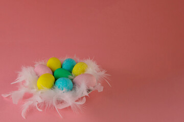 Happy Easter! Easter card with a picture of a nest of colored eggs of hen on a pink background