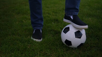 Fototapeta premium Man In Blue Jeans And Moccasins Juggling Black and White Classic Soccer Ball. People Go In For Sports. Young Boy Playing Football. Happy Family Team Have Spend Time At Park. Healthy Life, Championship