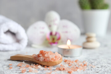 Obraz na płótnie Canvas Beauty and spa concept. Pink himalayan salt close-up on a wooden spoon with candle, orchid flower and towel. Selective focus