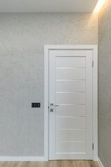 Classic white wooden door on a background of decorative plaster wall.