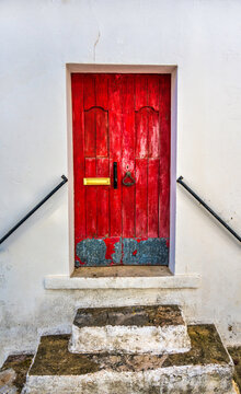 A Faded Bright Red Door With A Metal Kick Plate