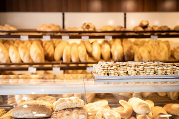 Bakery shop interior view and shelves full with freshly baked pastries, bread, bagels, muffin and cookies.