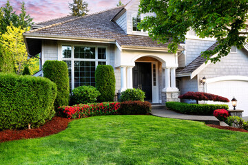 Beautiful home exterior in evening with healthy green lawn and flowerbeds - 498841733
