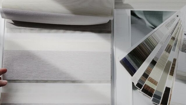 Woman fliping through catalog with roller blinds or window shade. Duo window roller system day and night. Choice of roller blinds.