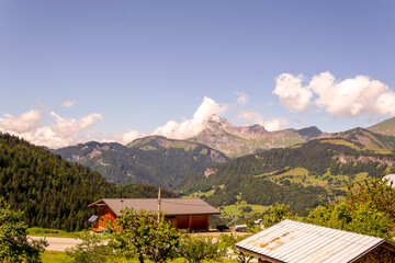 illustration d'un paysage de montagne avec un magnifique soleil et en premier plan des toiture de chalets 
	