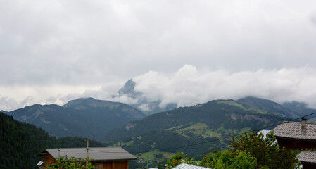 Fototapeta na wymiar illustration d'un paysage de montagne sous un ciel très nuageux avec plusieurs chalets 