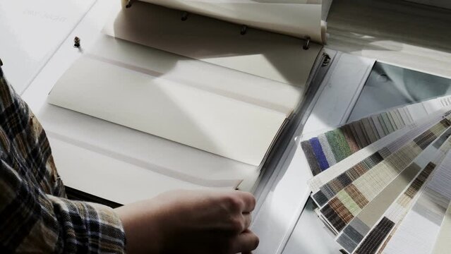 Woman fliping through catalog with roller blinds or window shade. Duo window roller system day and night. Choice of roller blinds.