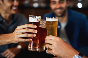 Well earned and ready to drink. Closeup of a group of young friends seated at a table together while enjoying a beer and celebrating with a celebratory toast inside a bar.