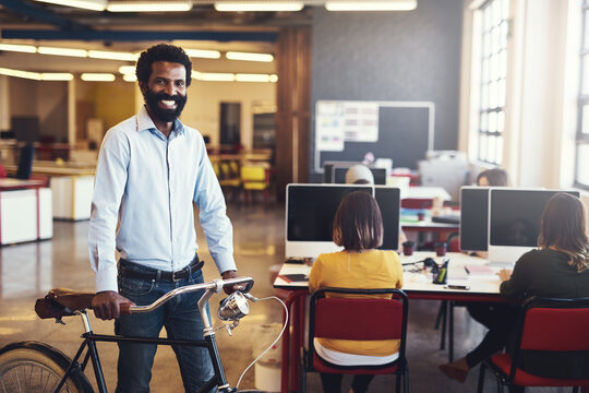 Live, Work, Create. Shot of a handsome man with a bicycle in a modern office.