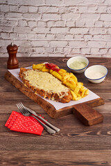 Typical Spanish food, cachopo with cheese, chips with sauces.