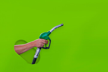 Man holds a refueling gun in his hand for refueling cars isolated on a green background. Gas...