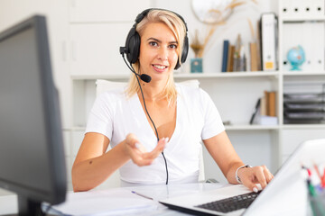 Naklejka premium Smiling female operator talking with customer using headset at company office