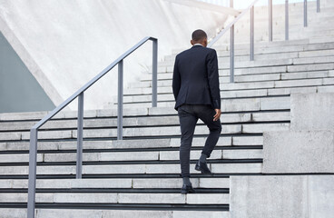 Walking up to success. Shot of an unrecognizable businessman walking up stairs in the city.