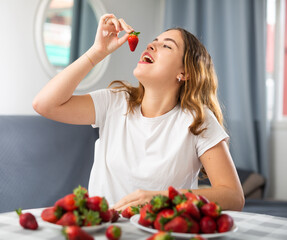 Portrait of a happy woman with strawberries at the table in the room at home