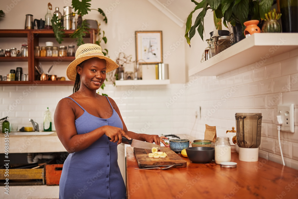 Poster God knows ive time to give. Portrait of a young beautiful woman wearing a sunhat while slicing fruit in the kitchen at home.