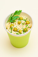 Prepared Instant Noodles with Green Pea and Greens in Green Cup on White Background. Guick Lunch or Unhealthy Fast Food