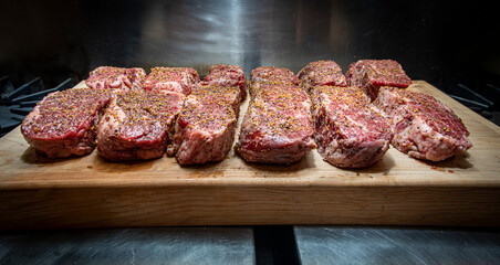 Twelve Seasoned Steaks on a cutting board in an industrial kitchen