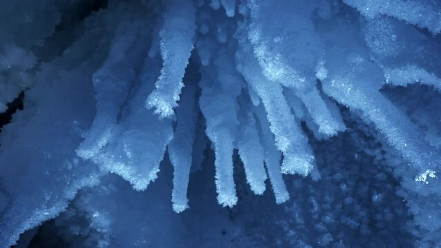 Beautiful crystal icicles, blue sharp ice floes inside frozen grotto 