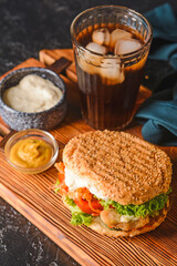 Fresh doner kebab in bun with sauces and glass of cola drink on dark background