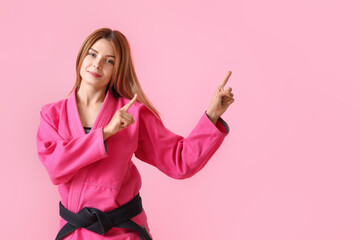 Female karate instructor pointing at something on color background © Pixel-Shot