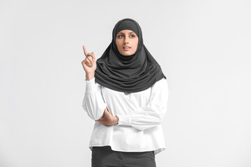 Muslim secretary with raised index finger on light background