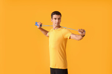 Sporty young man with jumping rope on color background