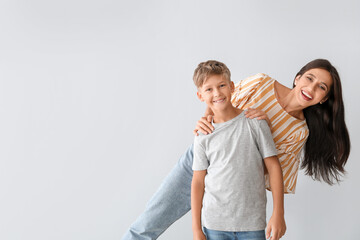 Happy woman and her son on light background