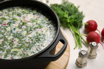 Cooking pot with tasty okroshka on light background, closeup