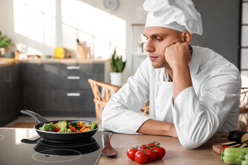 Tired male chef frying tasty vegetables in kitchen