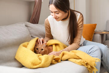 Woman with cute ginger cat at home on autumn day
