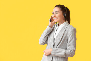 Pretty young businesswoman with headset on yellow background