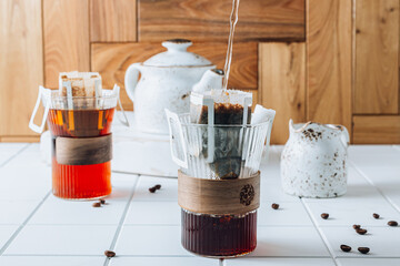 Ground drip coffee using paper type filter with coffee beans on white ceramic tiles background