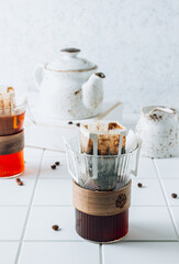 Ground drip coffee using paper type filter with coffee beans on white ceramic tiles background
